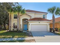 Two-story house featuring a terra cotta tile roof, a two-car garage, and a blue front door at 390 Miro Dr, Davenport, FL 33837