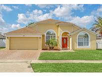 Inviting single-story home with a vibrant red front door, arched windows, and well-maintained landscaping at 477 Bohannon Blvd, Orlando, FL 32824