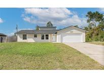 Charming single-story home with a well-manicured lawn, an attached two-car garage, and a welcoming front entrance at 1597 Lansfield Ave, Deltona, FL 32738