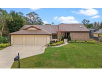 Charming one-story home with a three-car garage, lush landscaping, and a brick accent wall at 6766 Edgeworth Dr, Orlando, FL 32819