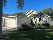 Charming single-story home with a two-car garage, lush landscaping, and healthy green grass under a clear blue sky at 8233 Westcott Shore Dr, Orlando, FL 32829