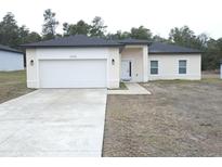 Charming single-Gathering home featuring a two-car garage, neutral stucco siding, and a well-maintained front yard at 13745 Sw 43Rd Cir, Ocala, FL 34473