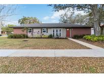 Charming one-story home featuring a brick facade, well-maintained lawn, and a welcoming red front door at 5359 Lanyard Ct, Winter Park, FL 32792