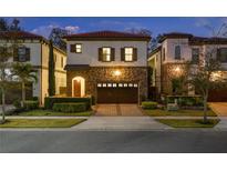 Beautiful two-story home featuring a stone facade and well-manicured landscaping at twilight at 8125 Via Vittoria Way, Orlando, FL 32819