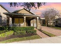 Home showcasing a cozy front porch, manicured landscaping, and a welcoming facade at 15174 Evergreen Oak, Winter Garden, FL 34787