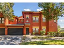 Two-story red townhouse with a black door, a garage and well-kept landscaping at 167 Villa Di Este Ter Ter # 213, Lake Mary, FL 32746