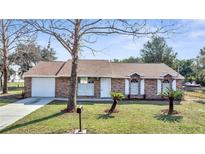 Charming brick home with a well-manicured lawn and a classic design with white trim around the windows at 23940 Oak Ln, Sorrento, FL 32776