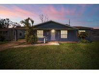 Charming single-story home with lush green lawn, mature trees, and inviting covered porch with decorative support columns at 4363 Cassius St, Orlando, FL 32811