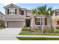 Charming two-story home featuring a tile roof, brown shutters, and a well-maintained front yard with tropical landscaping at 7845 Oak Reflection Loop, Davenport, FL 33837