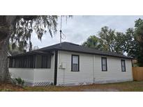 Charming home exterior featuring a screened porch, crisp white siding, and black trim under a cloudy sky at 812 S Locust Ave, Sanford, FL 32771