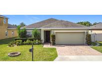 Charming single-story home with a well-manicured lawn and brick-paved driveway at 123 Vitoria Rd, Davenport, FL 33837