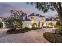 Elegant two-story home with a circular driveway, lush landscaping, and a welcoming entrance, perfect for luxurious living at 1355 S Summerlin Ave, Orlando, FL 32806