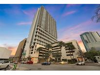 Modern high-rise condo building with sleek architecture, palm trees, and vibrant sunset sky at 150 E Robinson St # 2602, Orlando, FL 32801