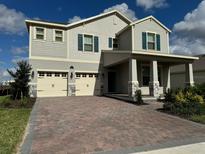 Two-story home with brick paver driveway, a two-car garage, blue shutters and a covered front porch at 18417 Oliver Twist Way, Winter Garden, FL 34787