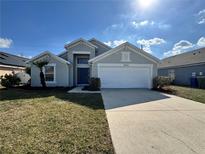 Two-story home with a two-car garage, blue front door, landscaped yard, and well-maintained lawn at 2932 Trema Ave, Winter Haven, FL 33881