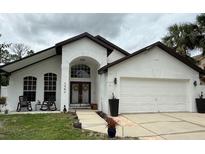 Charming home featuring a stucco exterior, arched entryway, well-manicured lawn, and attached two-car garage at 322 N Shadowbay Blvd, Longwood, FL 32779