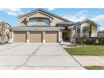 Two-story home with a tan exterior and a three-car garage with a well-maintained lawn and landscaping at 3262 Amaca Cir, Orlando, FL 32837