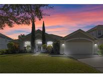 Charming single-story home features manicured lawn, mature landscaping, and a two-car garage at dusk at 644 Strihal Loop, Oakland, FL 34787