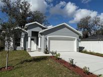 Charming single Gathering home featuring a pristine two car garage, manicured lawn, and freshly painted gray exterior at 1012 India Ave, Haines City, FL 33844