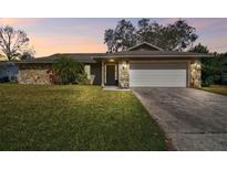 Charming single-story home featuring a stone facade and well-manicured lawn at 104 E Cottesmore Cir, Longwood, FL 32779