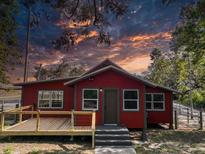 Charming exterior of a red home featuring a modern porch and a beautiful sunset backdrop at 111 Water Tank Rd, Haines City, FL 33844