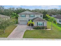 Charming two-story home with a well-manicured lawn, brick driveway, and mature landscaping at 3819 Breckinridge Ln, Clermont, FL 34711