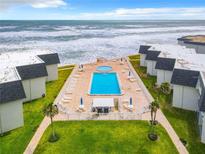 Aerial view of oceanfront condos with a large pool and manicured green space at 4831 Saxon Dr # 1130, New Smyrna Beach, FL 32169