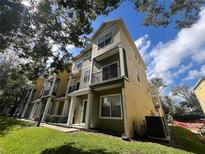 Attractive, multi-story townhome featuring private balconies and manicured lawns under a sunny blue sky at 5 W Harding St # E, Orlando, FL 32806