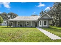 Charming single-story home featuring a metal roof, covered porch, and lush lawn at 5335 Canoe Creek Rd, St Cloud, FL 34772