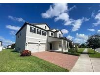 Two-story home with a two-car garage, brick paver driveway, and well-manicured lawn at 7606 Loon Ave, Winter Garden, FL 34787