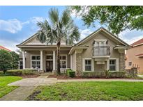 Charming home featuring a stone facade, elegant columns, a small balcony, and mature landscaping at 10742 Boca Pointe Dr, Orlando, FL 32836