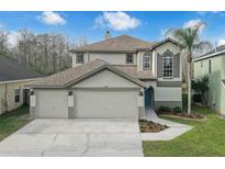 Beautiful two-story home boasts a three-car garage, manicured lawn, and welcoming entrance at 13631 Guildhall Cir, Orlando, FL 32828