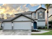 Charming two-story home featuring a three-car garage, well-maintained landscaping, and a beautiful blue entry door at 13631 Guildhall Cir, Orlando, FL 32828