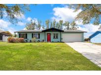 Charming single-story home with manicured lawn, bright red door, and attached garage at 1433 Ne Old Mill Dr, Deltona, FL 32725