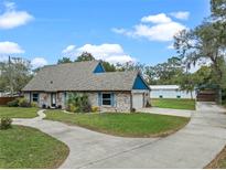 Charming single-story brick home with lush lawn, long driveway, detached garage, and blue trim at 1134 Glenwood Rd, Deland, FL 32720