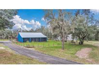 Charming blue home with a metal roof and inviting screened porch surrounded by lush greenery at 255 Butterfly Forest Rd, Geneva, FL 32732