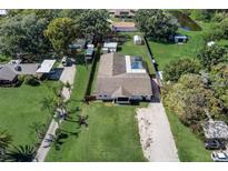An aerial view showcasing a well-maintained lot with a screen-enclosed pool and long driveway at 290 Orange Ave, St Cloud, FL 34769