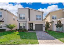Modern two-story home featuring a paver driveway, green lawn, and nicely manicured landscaping at 4374 Rhyme St, Kissimmee, FL 34746