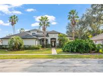 Stunning home exterior with lush landscaping and mature palm trees under a bright blue sky at 10400 Windermere Chase Blvd, Gotha, FL 34734