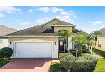 Charming home featuring a brick driveway, a two-car garage, and well-maintained landscaping with palm trees at 53 High Vista Dr, Davenport, FL 33837