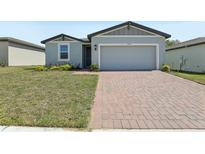 Charming single-Gathering home features a brick driveway, a 2-car garage, and well-maintained lawn at 1522 Mermaid Way, Haines City, FL 33844