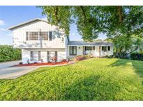 Beautifully landscaped two-story home featuring a well-manicured lawn and a charming front porch with rocking chairs at 2807 Hoffner Ave, Belle Isle, FL 32812