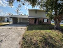 Two story exterior with brick accents, mature trees, and covered parking area at 3540 Westwood Ave, Winter Haven, FL 33880
