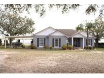 Charming single-story home with a grey exterior, a boat port, and lush landscaping at 9130 Laws Rd, Clermont, FL 34714