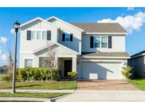Charming two-story home with landscaped yard, brick driveway, and an attached garage at 9228 Halsey Dr, Groveland, FL 34736
