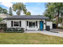 Charming single-story home featuring a blue front door, two white rocking chairs, and a well-maintained lawn at 1410 Osceola Ct, Orlando, FL 32806