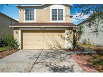 Beige two-story home with a tan garage, red roof and neatly kept yard on a sunny day at 15323 Torpoint Rd, Winter Garden, FL 34787