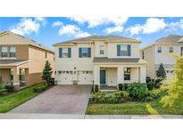 Charming two-story home featuring a brick driveway, manicured lawn, and a welcoming front porch with blue door at 17846 Adrift Rd, Winter Garden, FL 34787