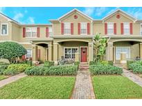 Inviting townhouse with brick pathway, manicured lawn, covered porch, and red shutters at 9130 Sabal Pine Way, Orlando, FL 32832