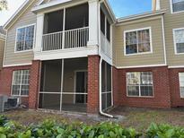 Tan two-story condo with red brick accents and a screened-in porch, offering outdoor living space at 13028 Plantation Park Cir # 1218, Orlando, FL 32821